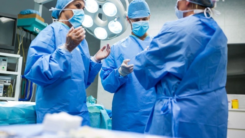 Surgeons in blue robes getting ready to perform a surgical intervention