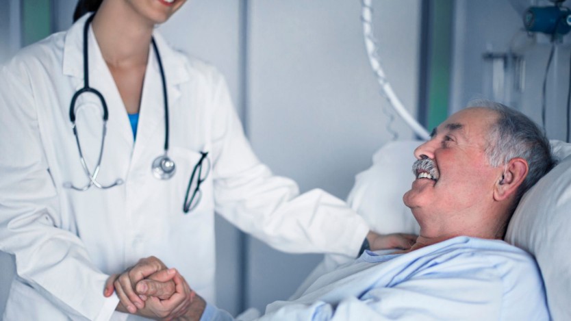 Elderly patient in a hospital bed chatting with his doctor