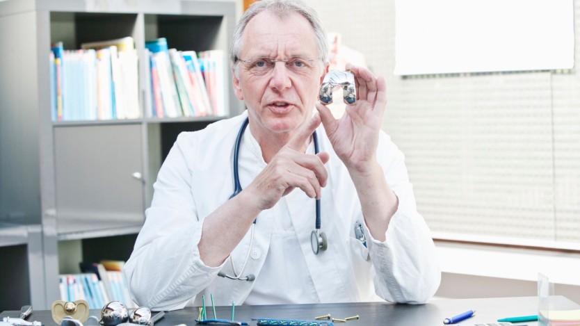 Specialist holding a part of a prosthesis for the knee
